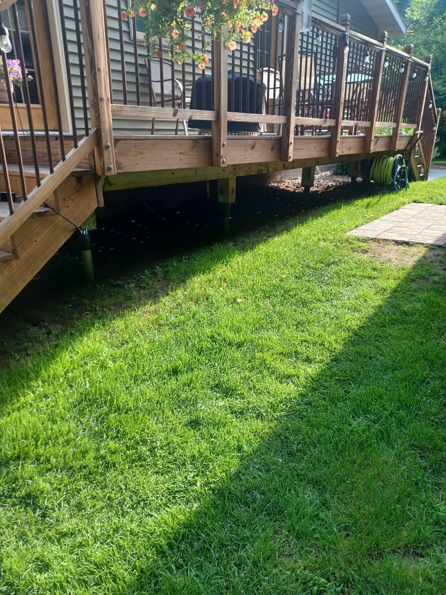 A wooden deck with stairs is sitting on top of a lush green lawn.