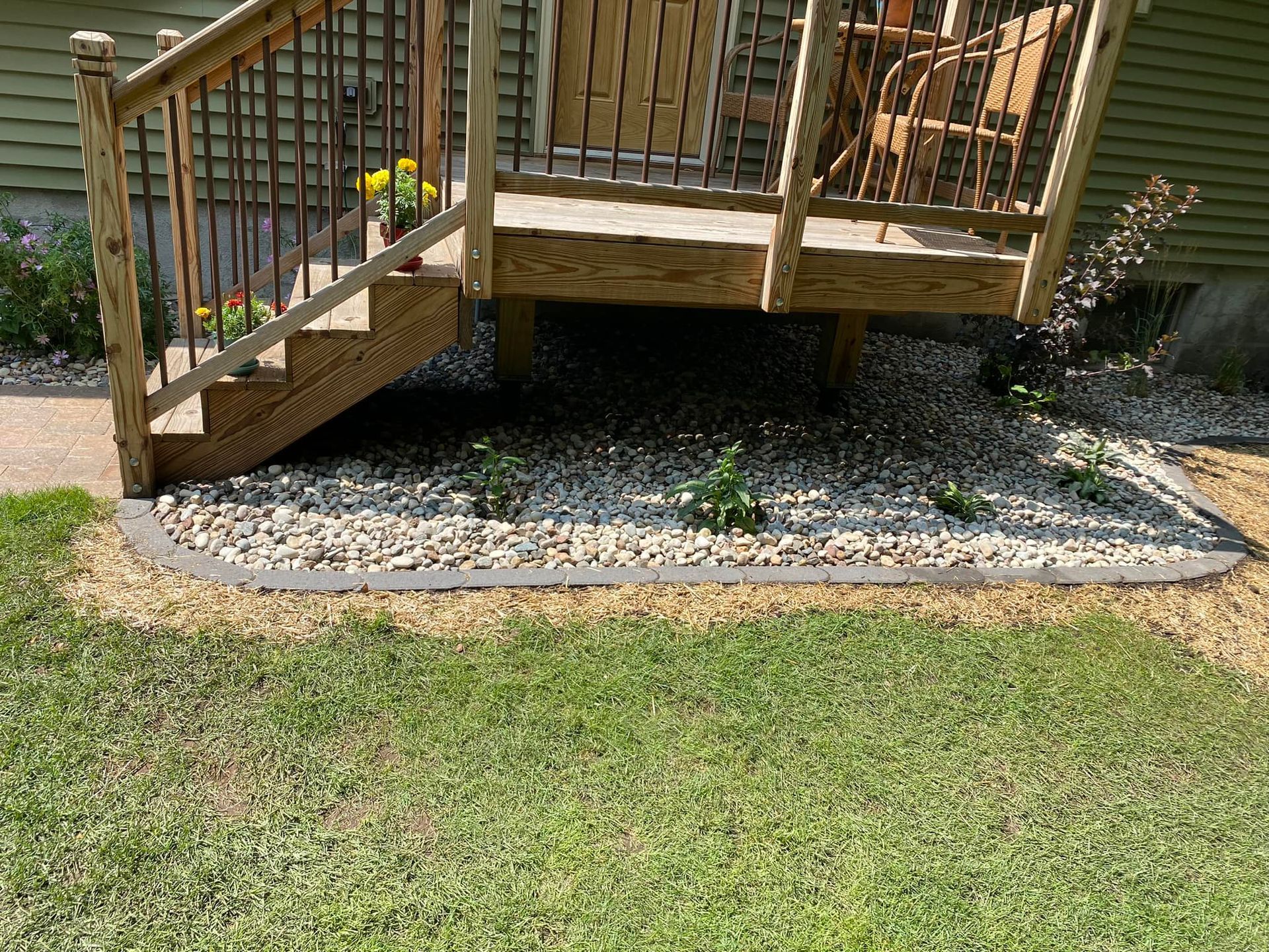 A wooden deck with stairs leading up to it is sitting on top of a lush green lawn.