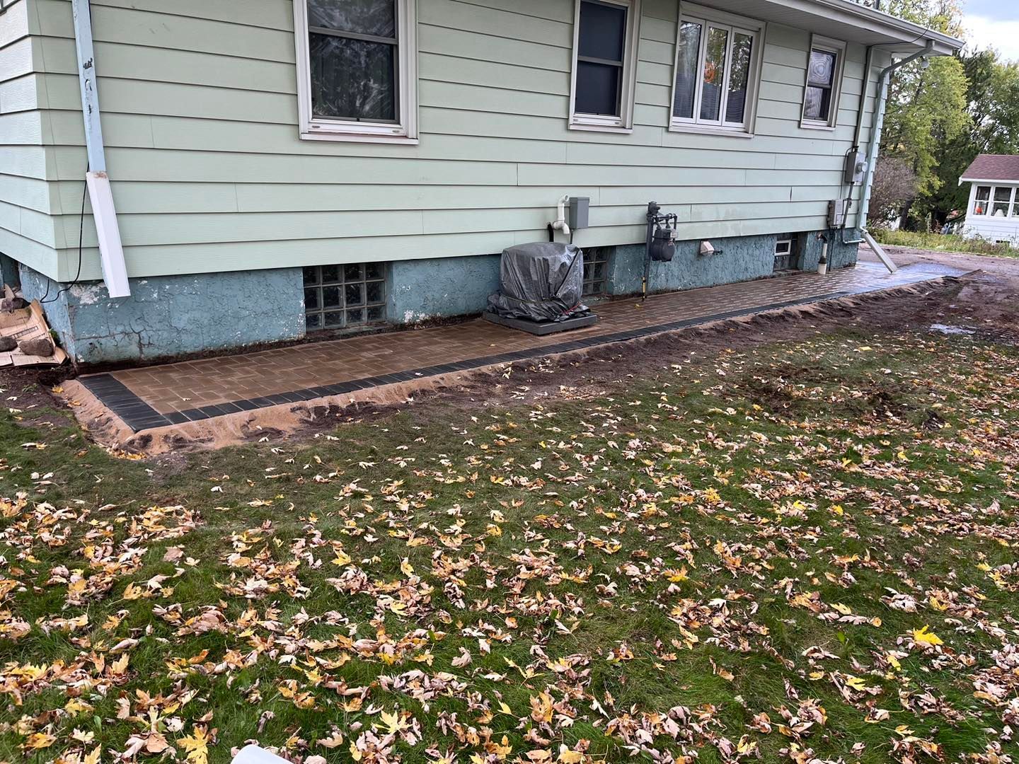 A house with a patio in front of it and a lot of leaves on the ground.