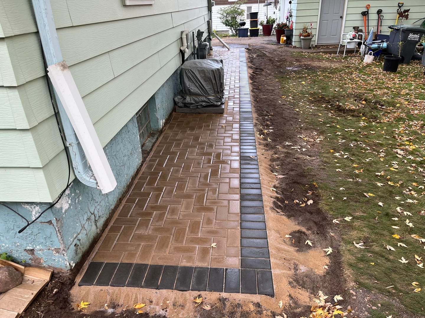A brick walkway is being built in front of a house.