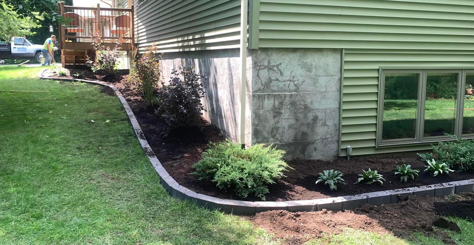 A house with a green siding and a lawn in front of it.