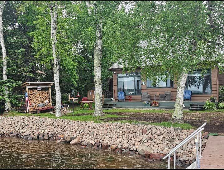 A small house is sitting on the shore of a lake surrounded by trees.