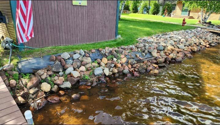 A river with rocks on the side of it and a house in the background.