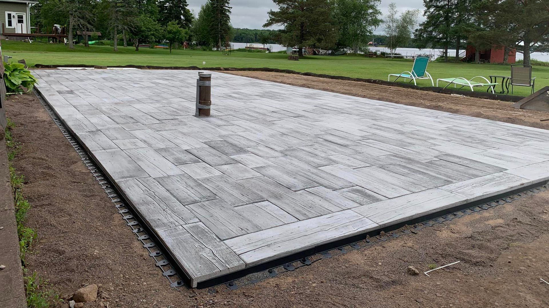 A large concrete patio is being built in a backyard.