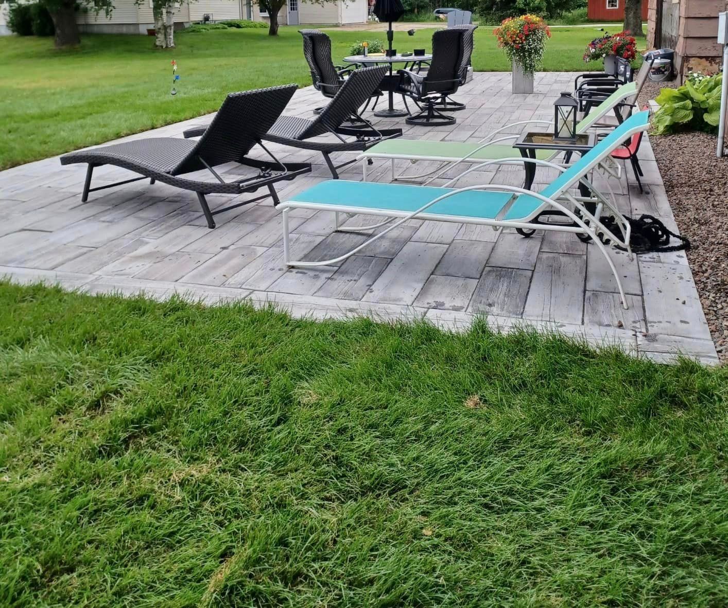 A patio with lawn chairs and tables in the grass.