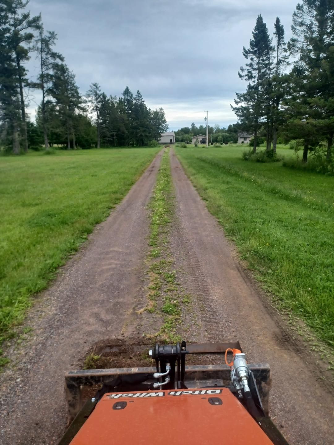 A tractor is driving down a dirt road in a field