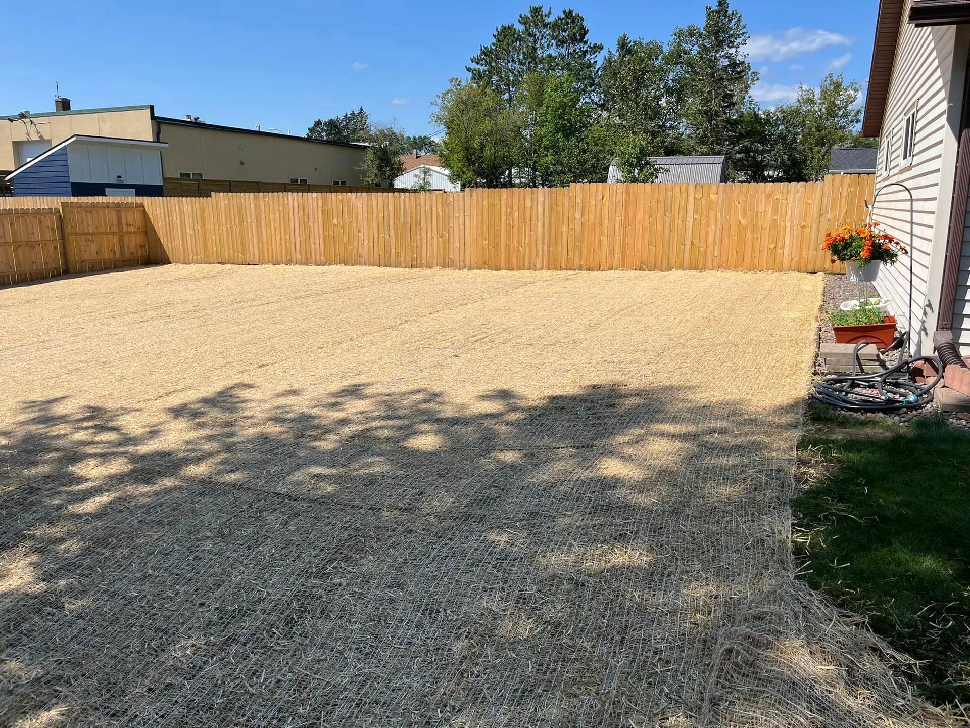 A backyard with gravel and a wooden fence