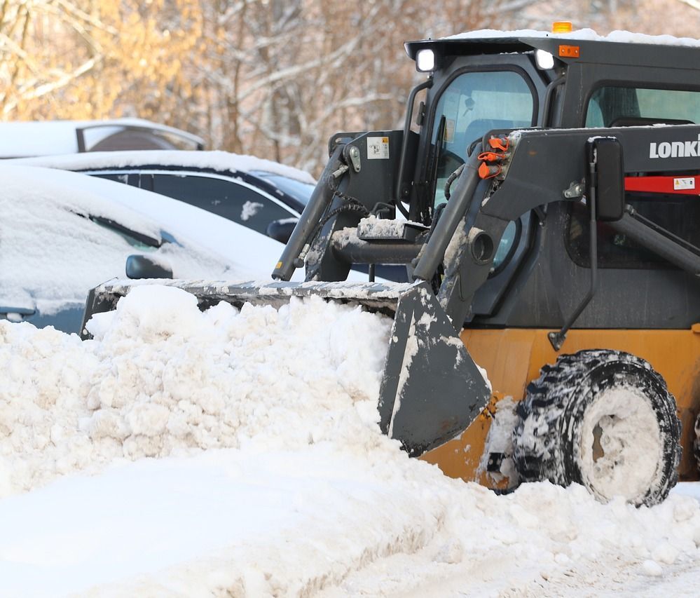 A snow plow is clearing snow from a parking lot