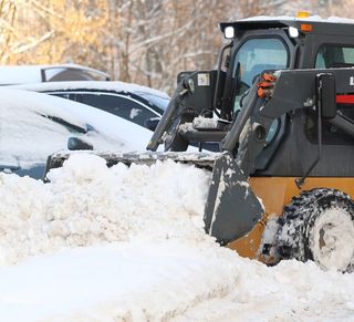 A snow plow is clearing snow from a parking lot