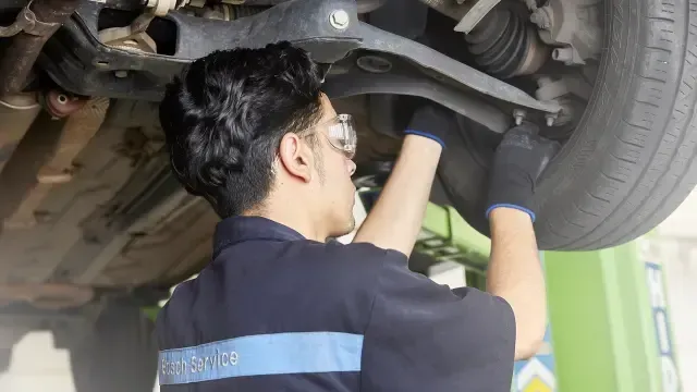 Un hombre está trabajando debajo de un coche en un garaje.
