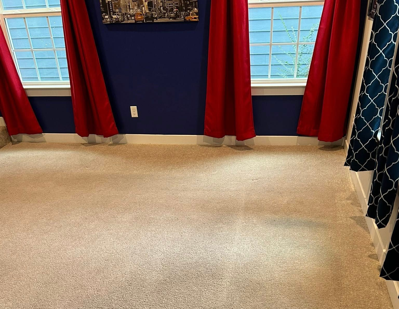 Beige speckled carpeted room with dark blue walls, red curtains, and windows.