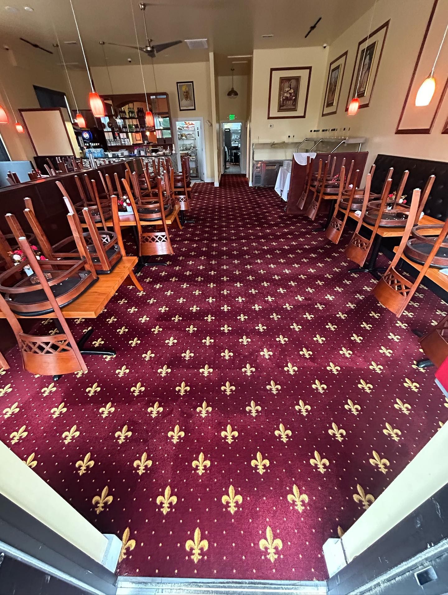 Restaurant interior with red carpet and chairs stacked on tables.