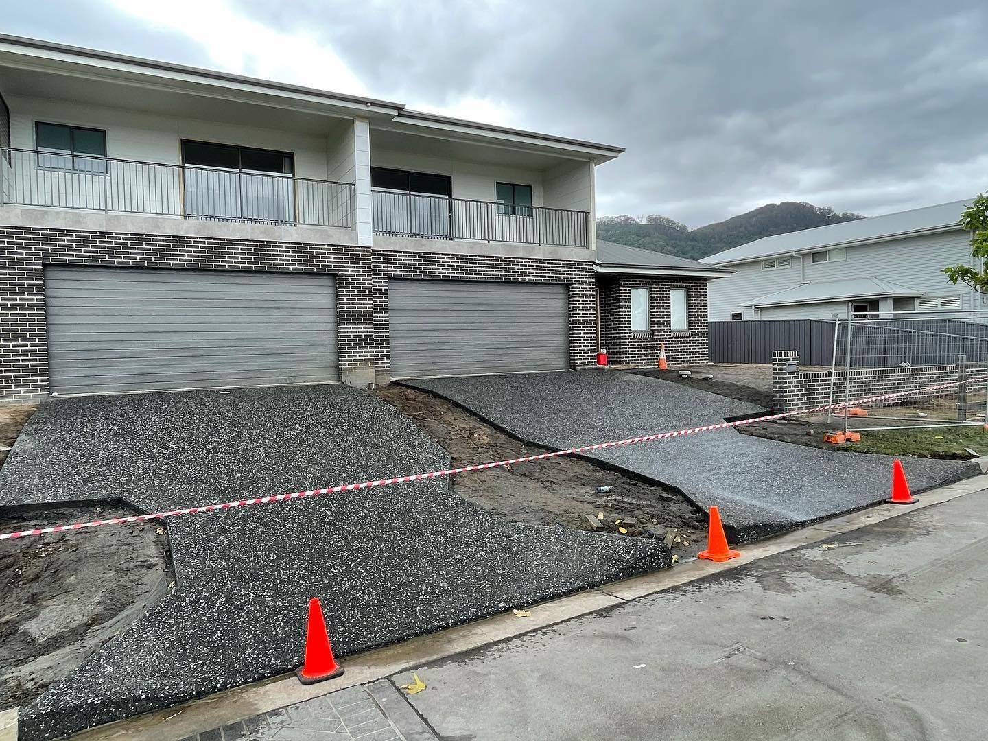A Two-story Building Under Construction With Newly Poured Aggregate Concrete Driveways — JDB Concreting in Horsley, NSW