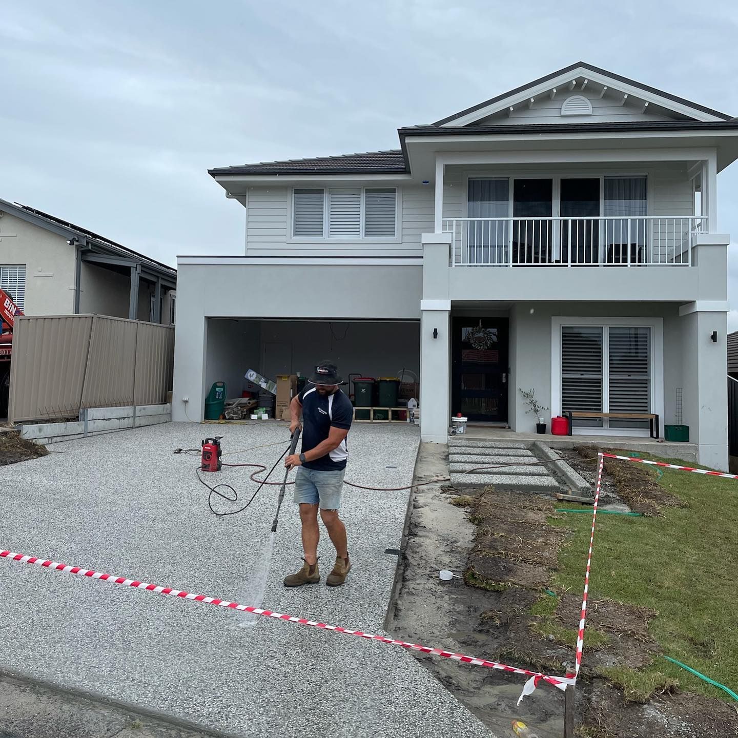 A Person Power-washes a Light Gray Stone Driveway — JDB Concreting in Horsley, NSW
