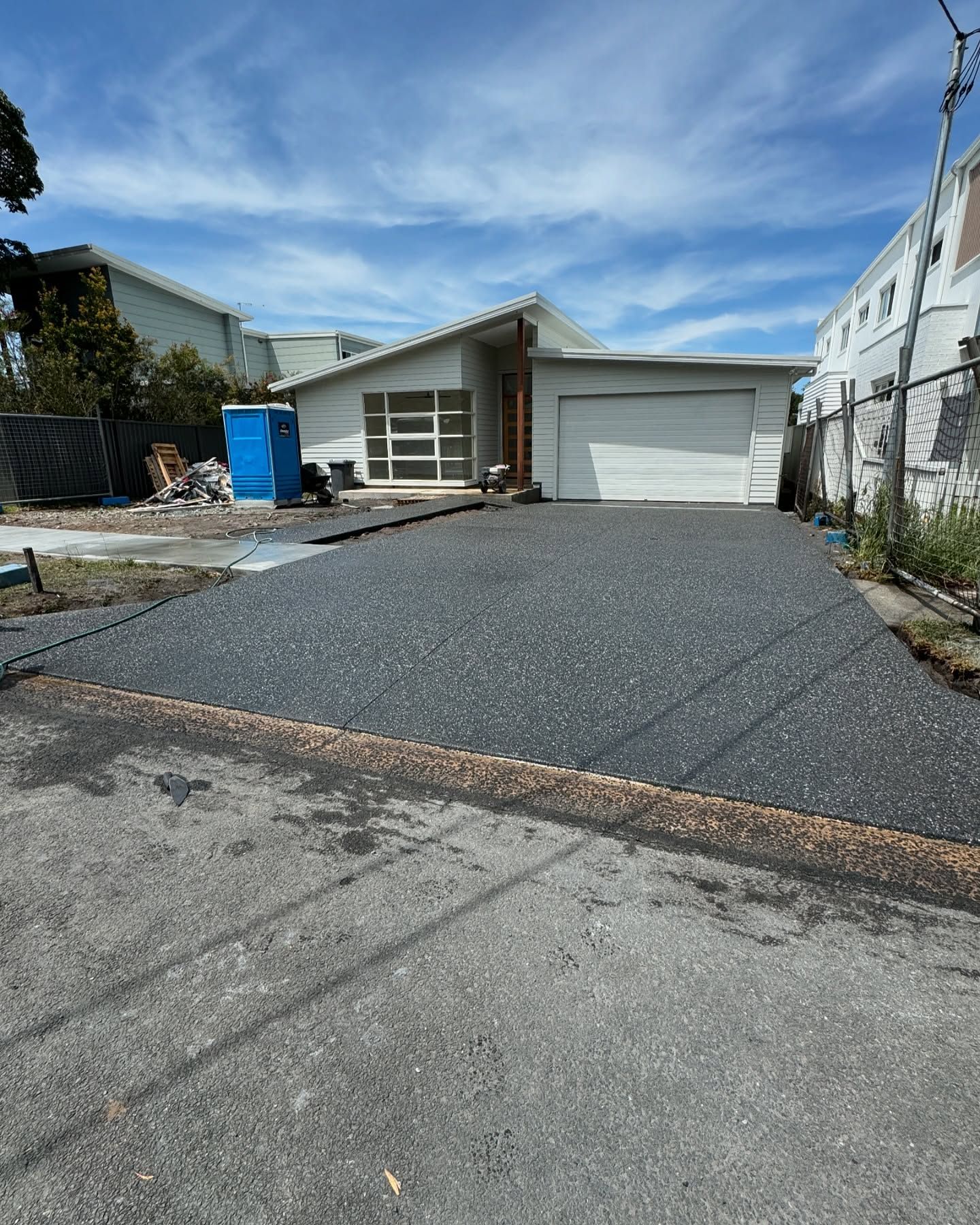 A Modern Suburban House With a White Garage and a Newly Paved, Dark, Speckled Driveway — JDB Concreting in Horsley, NSW