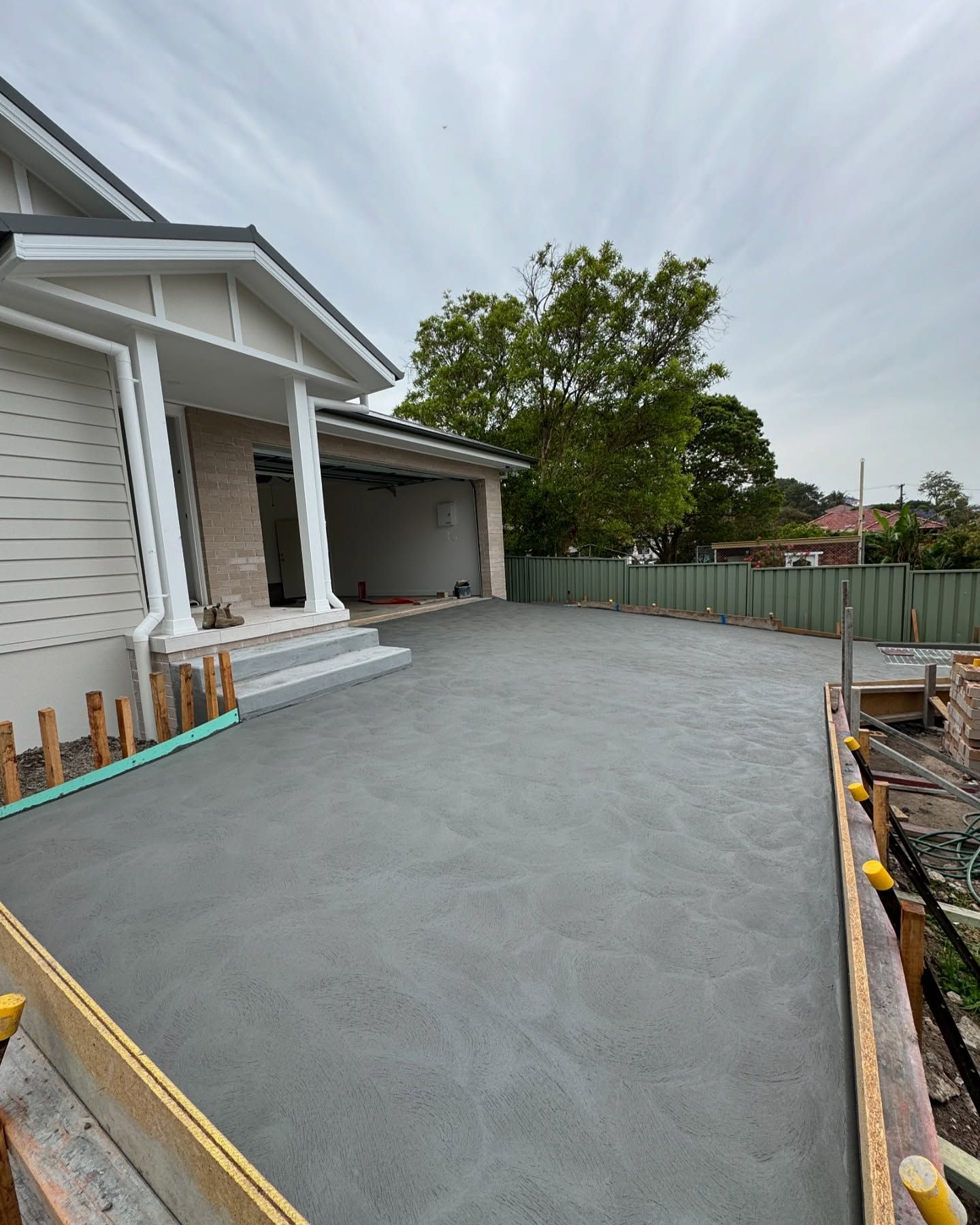 Freshly Poured Gray Concrete Driveway in Front of a Residential House — JDB Concreting in Southern Highlands, NSW