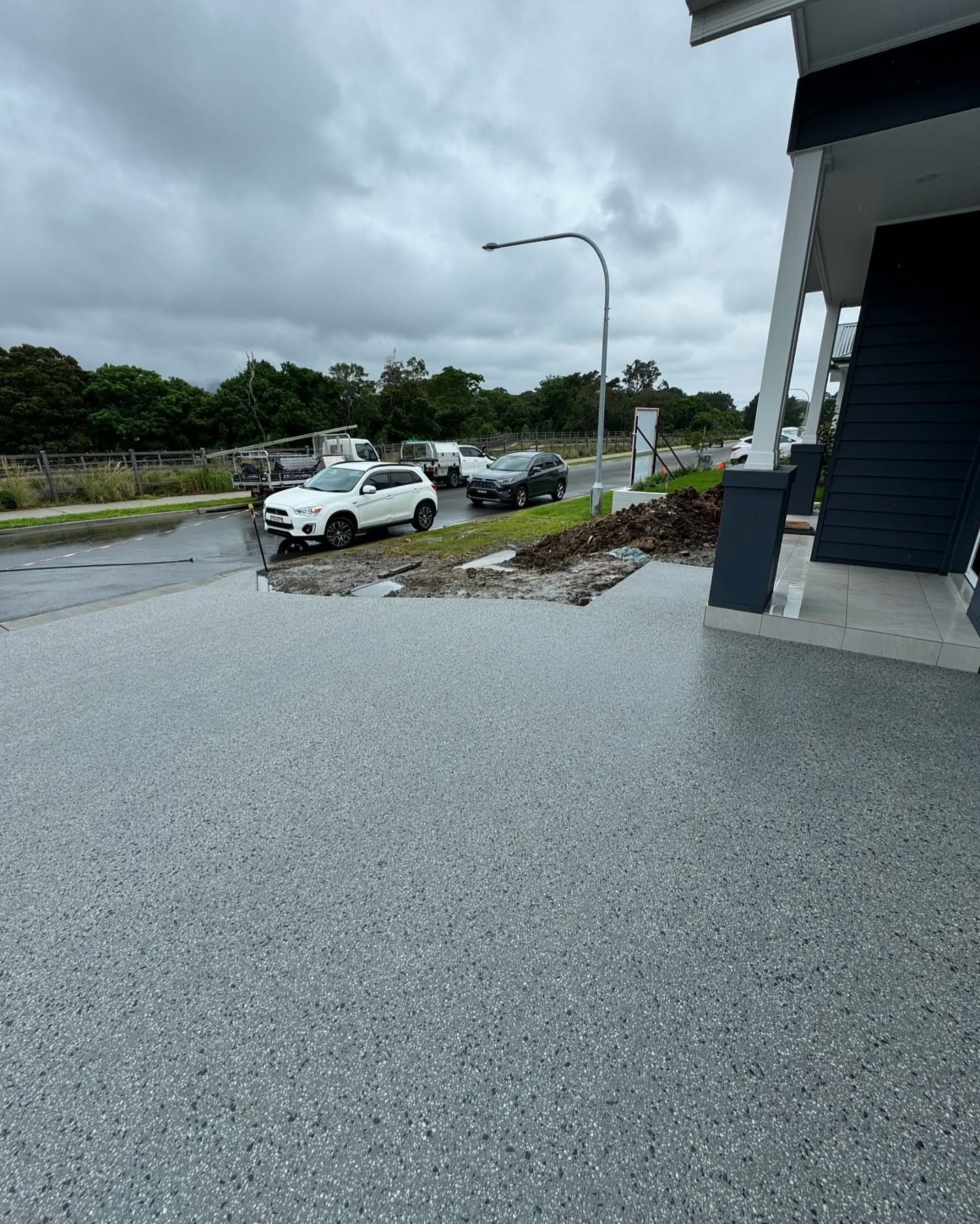 A Light Gray, Speckled Epoxy Patio Floor Overlooking a Wet Street — JDB Concreting in Shellharbour, NSW