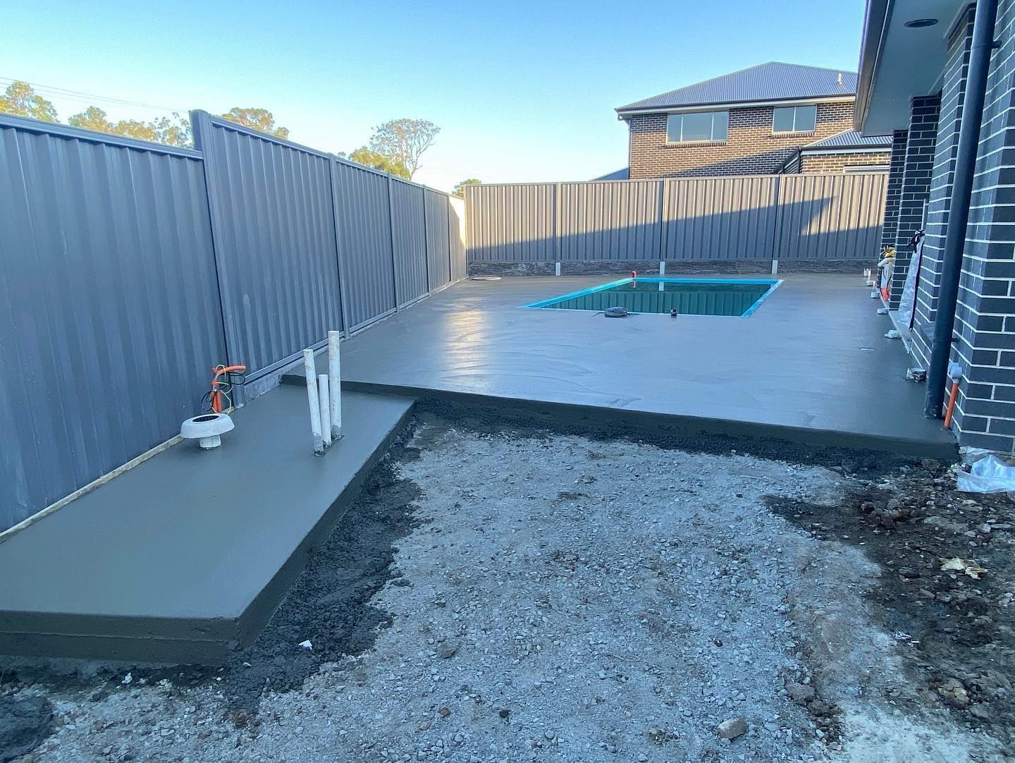 A Freshly Poured Concrete Patio Surrounds a Small Rectangular Swimming Pool — JDB Concreting in Horsley, NSW
