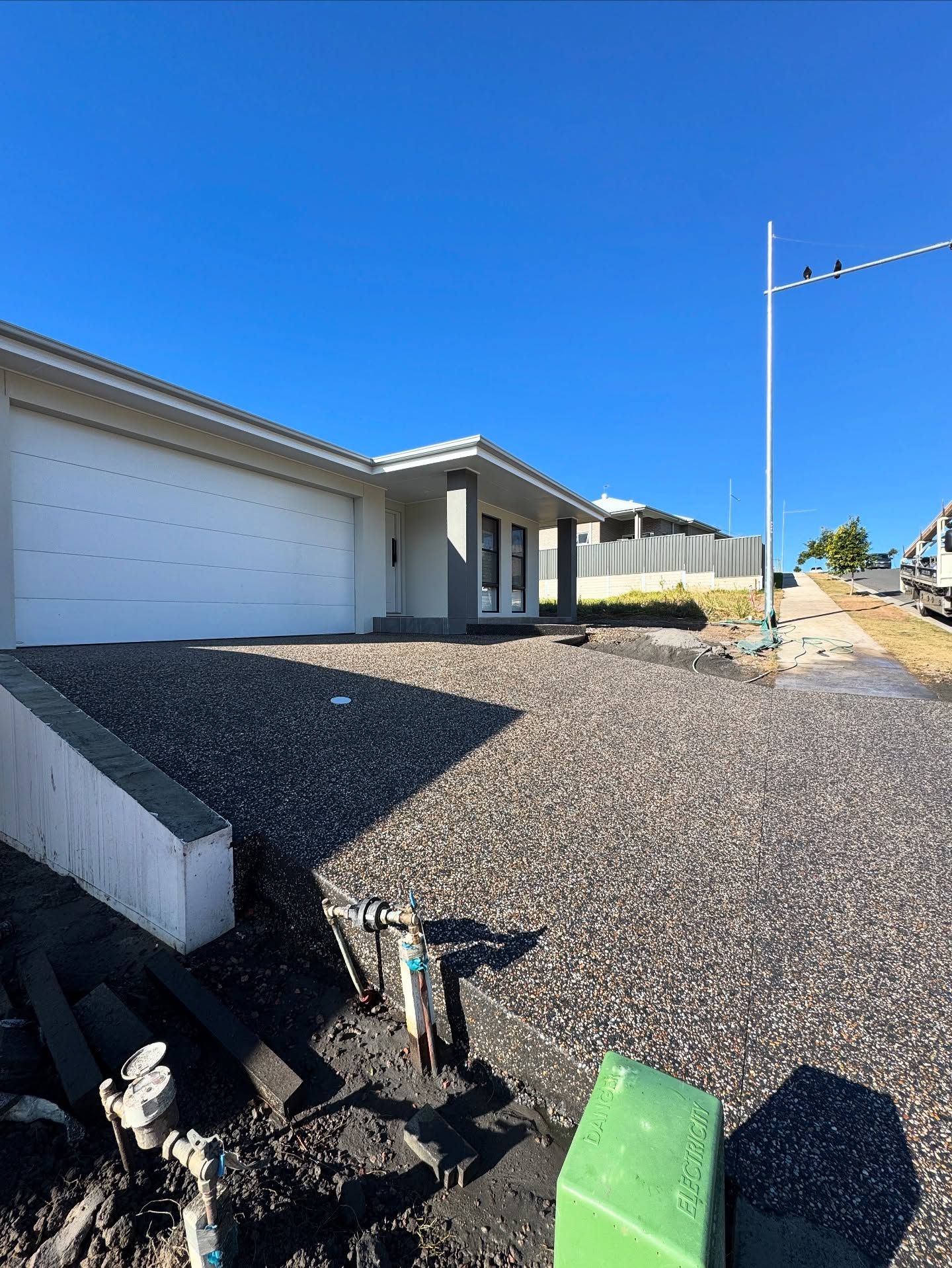 A Newly Constructed, Single-story Light-coloured House With a Gravel Driveway — JDB Concreting in Albion Park, NSW