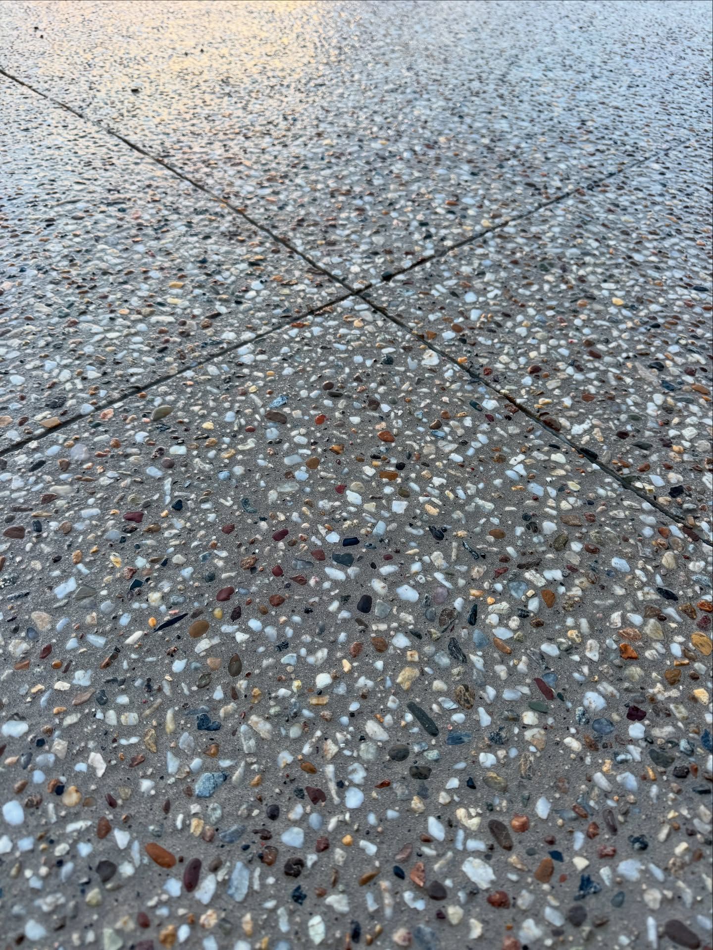 A Close-up of a Gray Concrete Surface With Embedded Multi-coloured Pebbles — JDB Concreting in Shellharbour, NSW