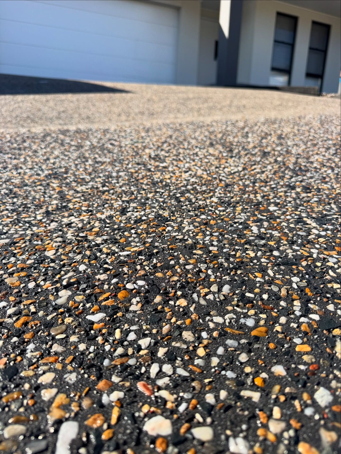 Close-up of a Dark, Textured Exposed Aggregate Concrete Driveway — JDB Concreting in Albion Park, NSW
