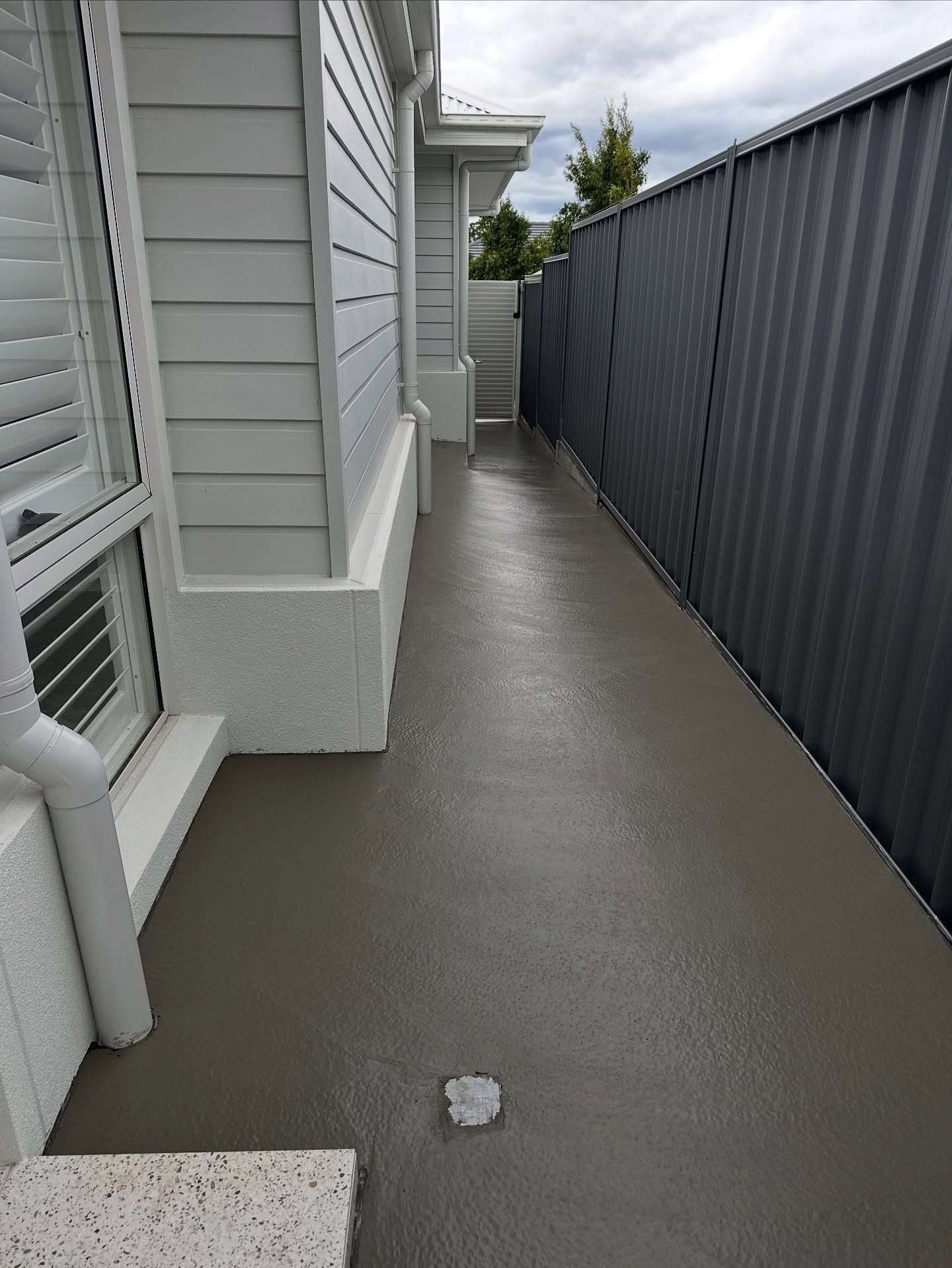 A Newly Poured Gray Concrete Side Path Between a White House Wall — JDB Concreting in Albion Park, NSW