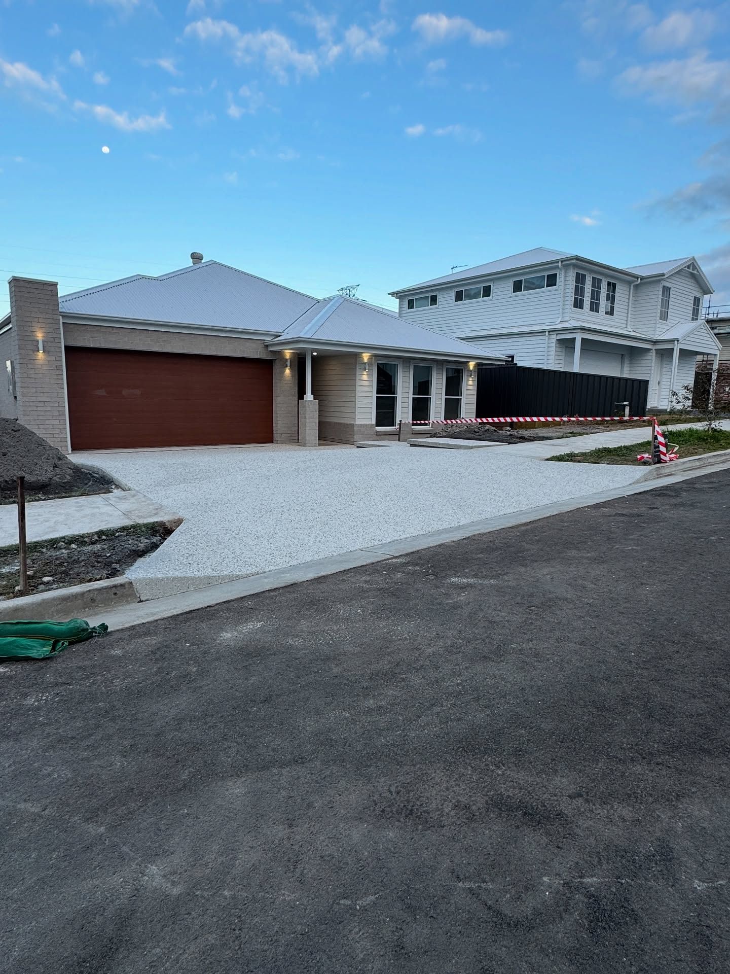 A Modern Single-story House With a Reddish-brown Garage Door and Light-coloured Siding — JDB Concreting in Dapto, NSW