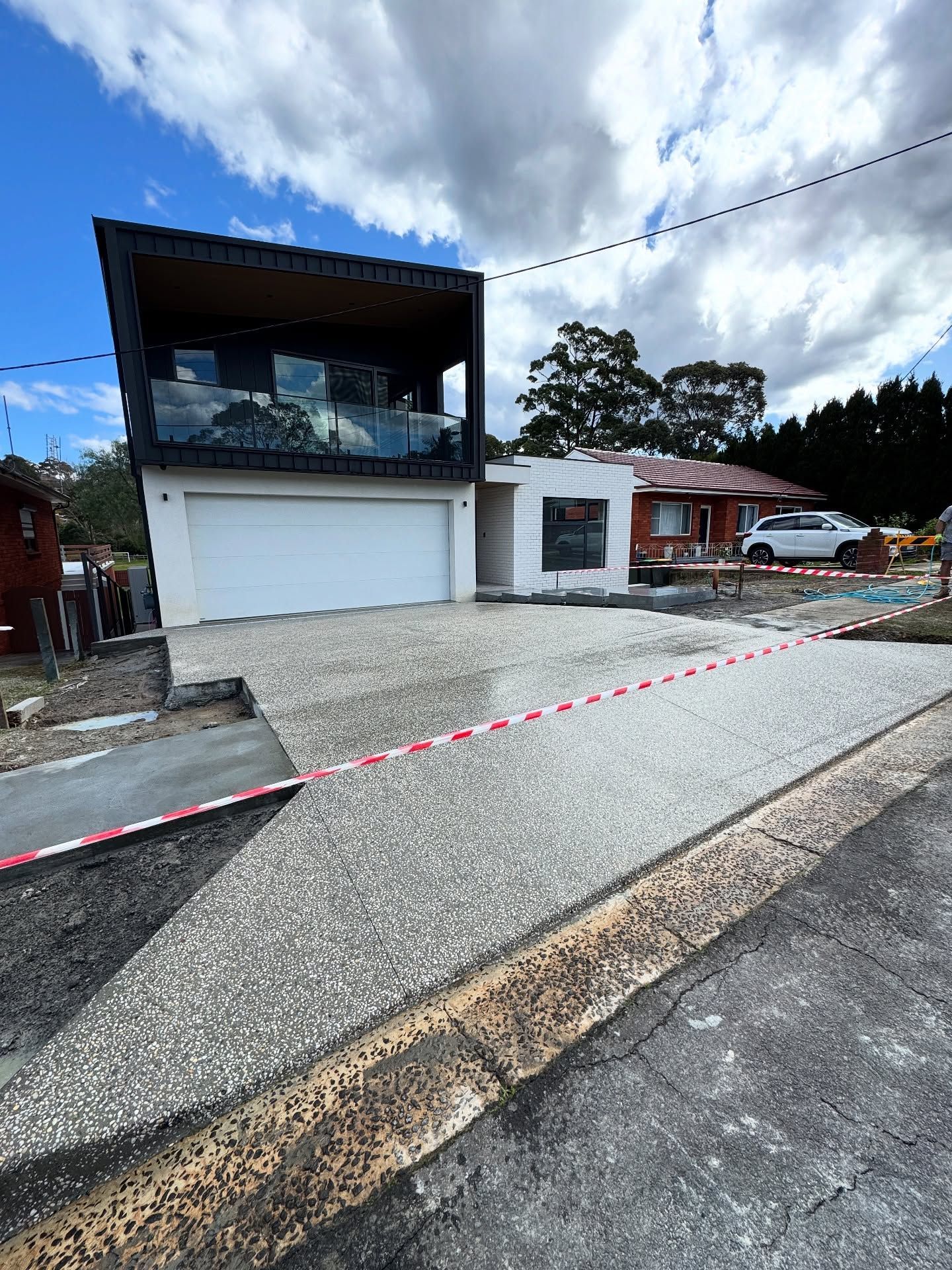 A Two-story Home Sits Behind a Newly Poured Exposed Aggregate Concrete Driveway — JDB Concreting in Woonona, NSW