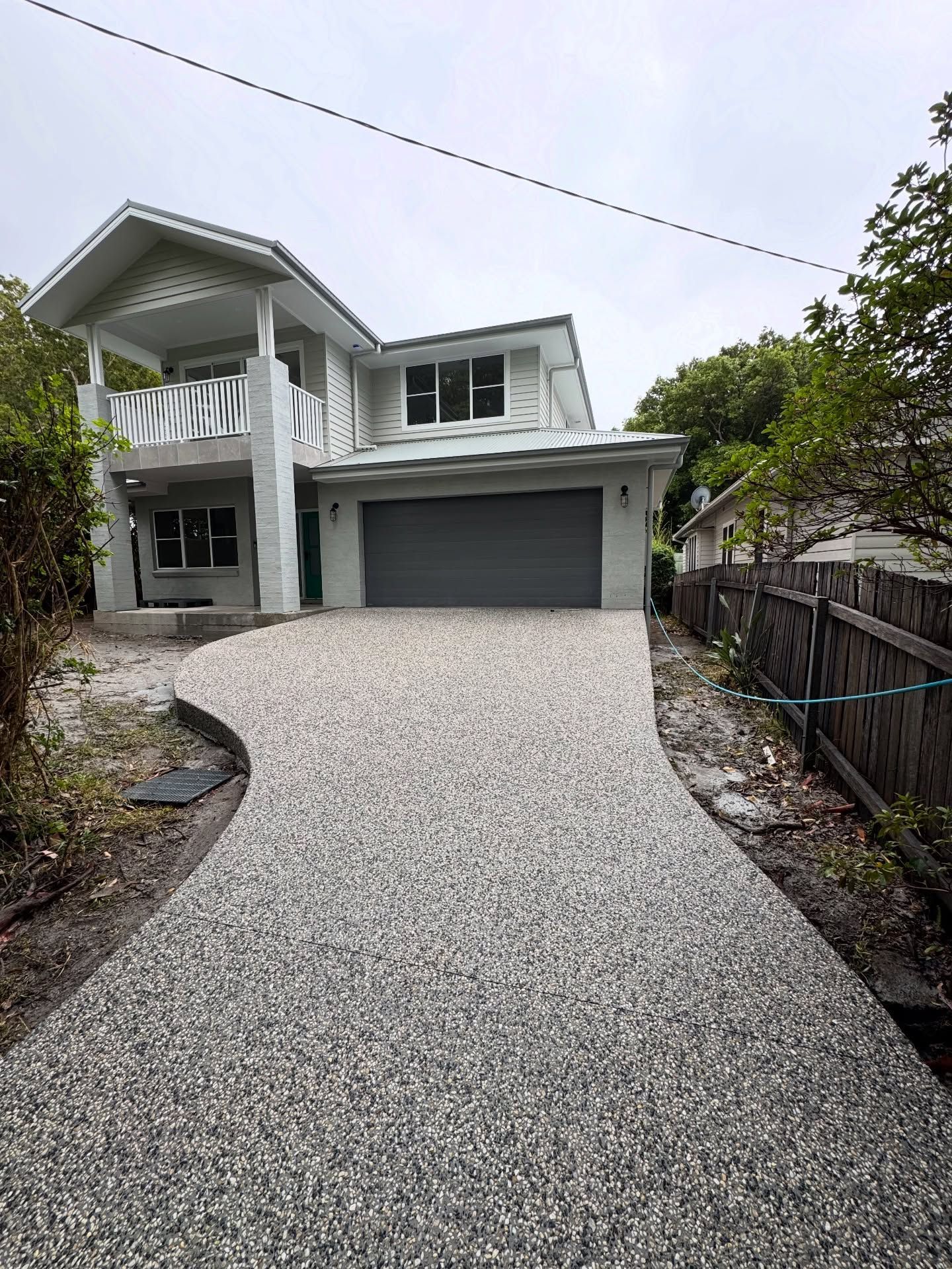 A Two-story Light Gray House With a Modern Garage and a Curved, Exposed Aggregate Driveway — JDB Concreting in Thirroul, NSW
