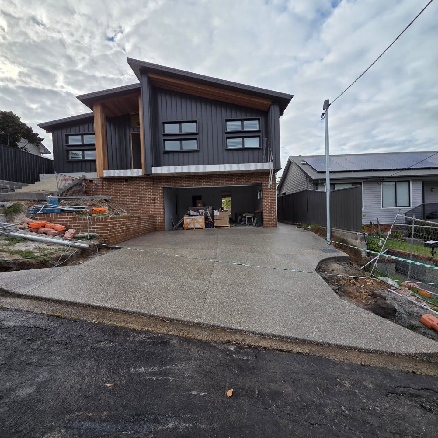 A Modern Two-story Home With Dark Metal Cladding and a Brick Base — JDB Concreting in Wollongong, NSW