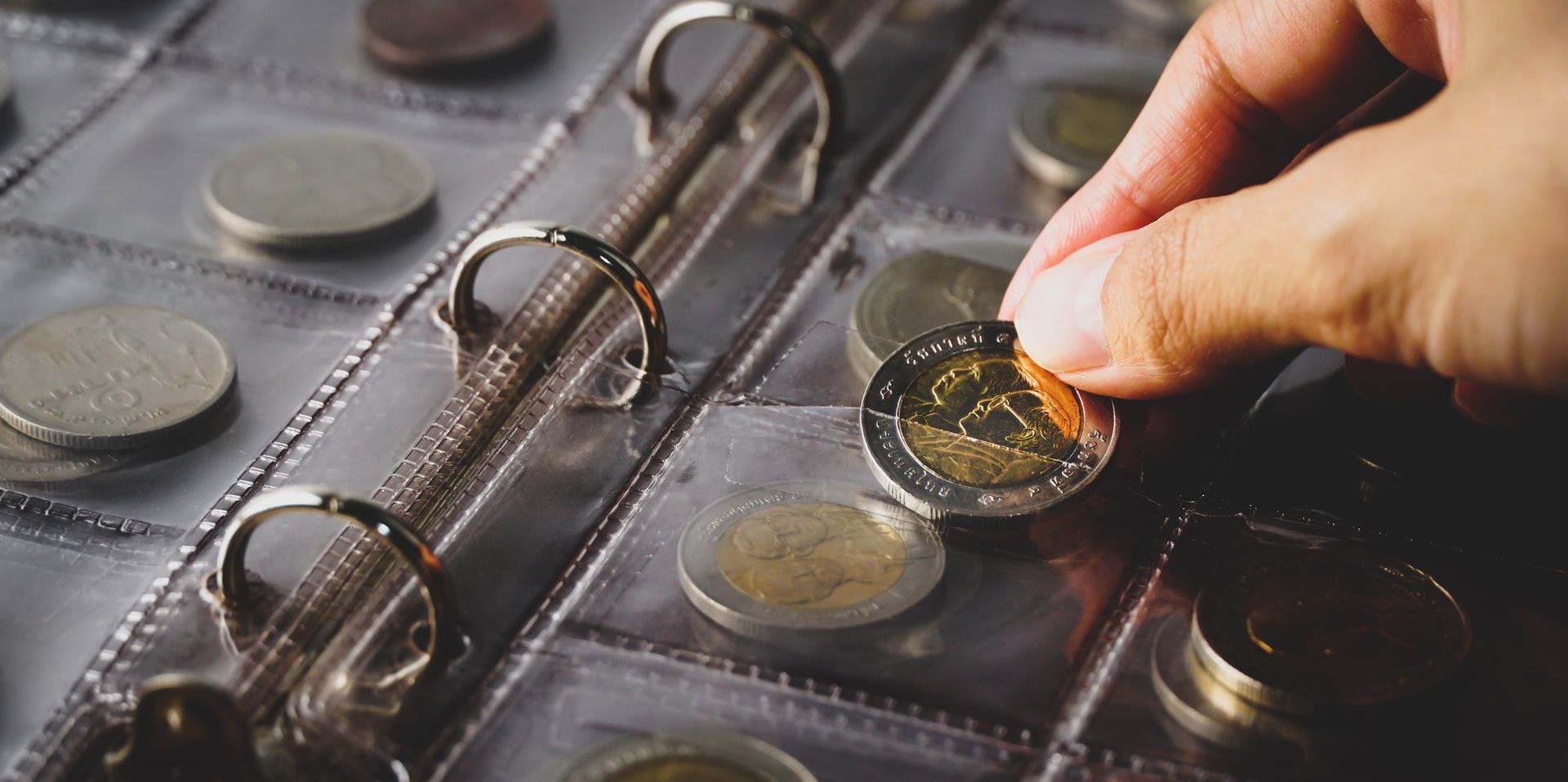 Hand placing a coin into a plastic coin album page.