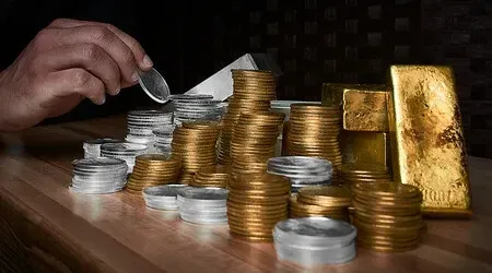 Three gold bars are stacked on top of each other on a blue surface.