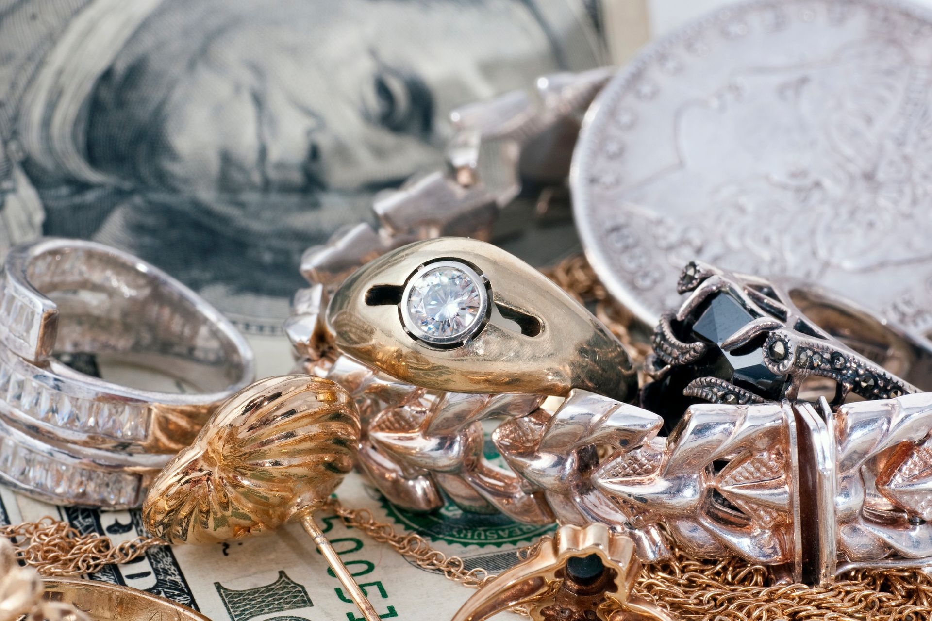 A pile of gold jewelry is sitting on top of a dollar bill.