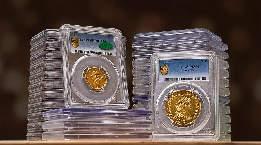 Two gold coins in plastic cases are stacked on top of each other on a table.