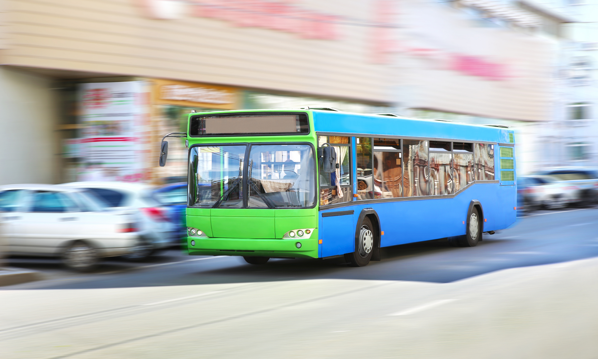 A blue and green bus is driving down a city street.