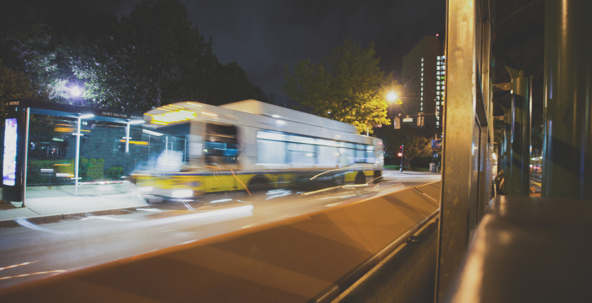 A bus is driving down a city street at night.