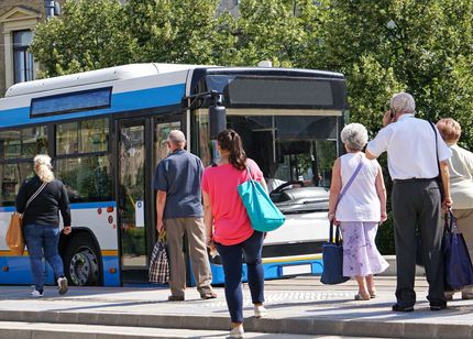 A group of people are boarding a bus at a bus stop.