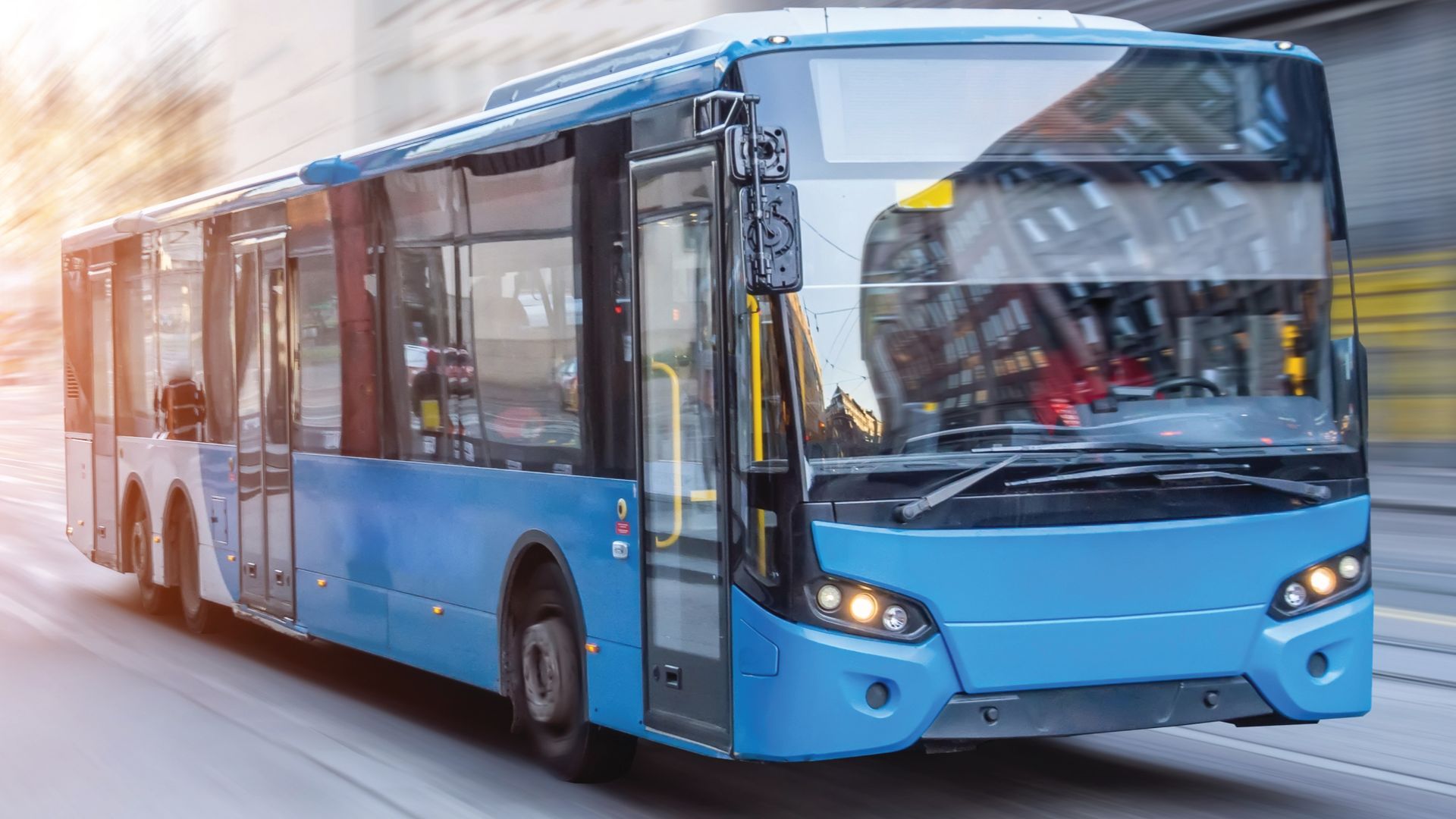 A blue bus is driving down a city street.