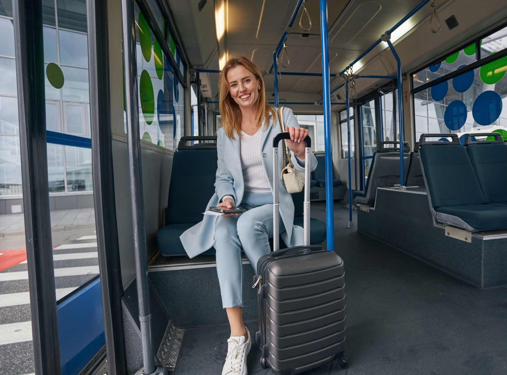 A woman is sitting on a bus with a suitcase.