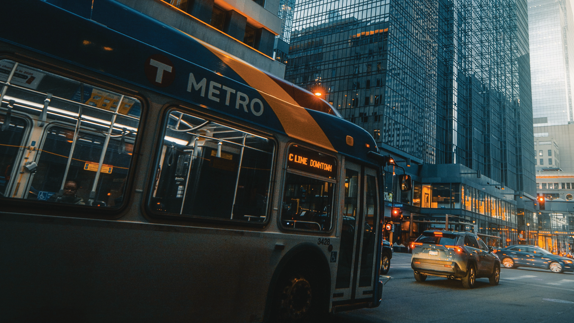 A bus is driving down a city street next to a building.