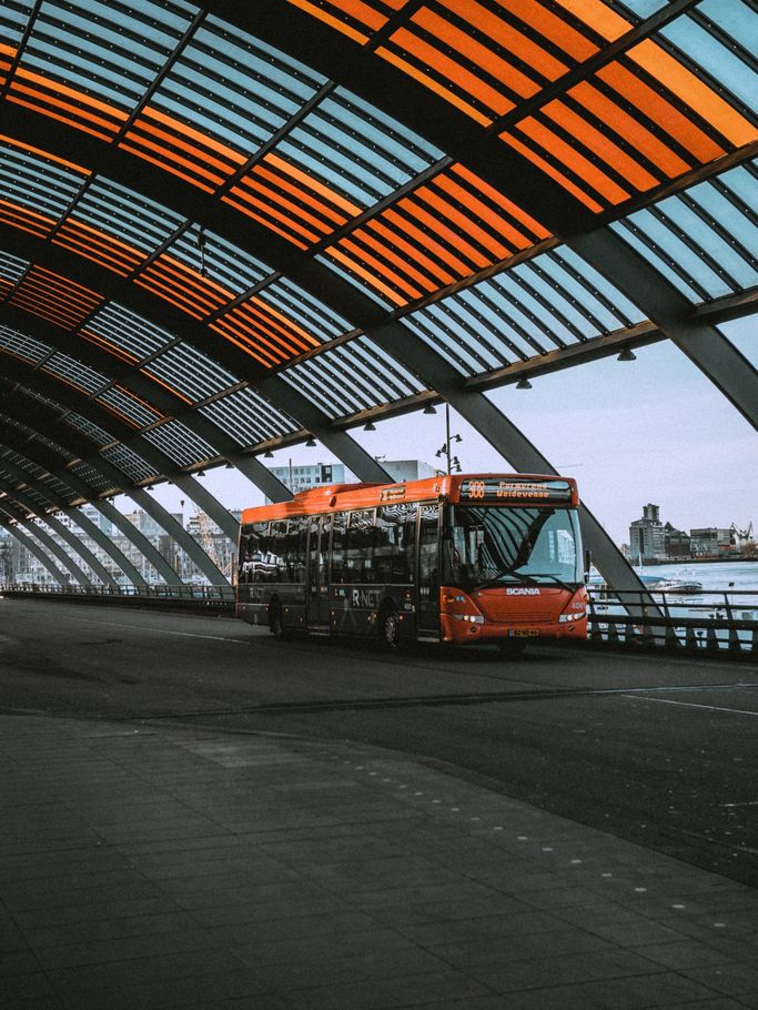 A bus is parked under a bridge with a colorful roof