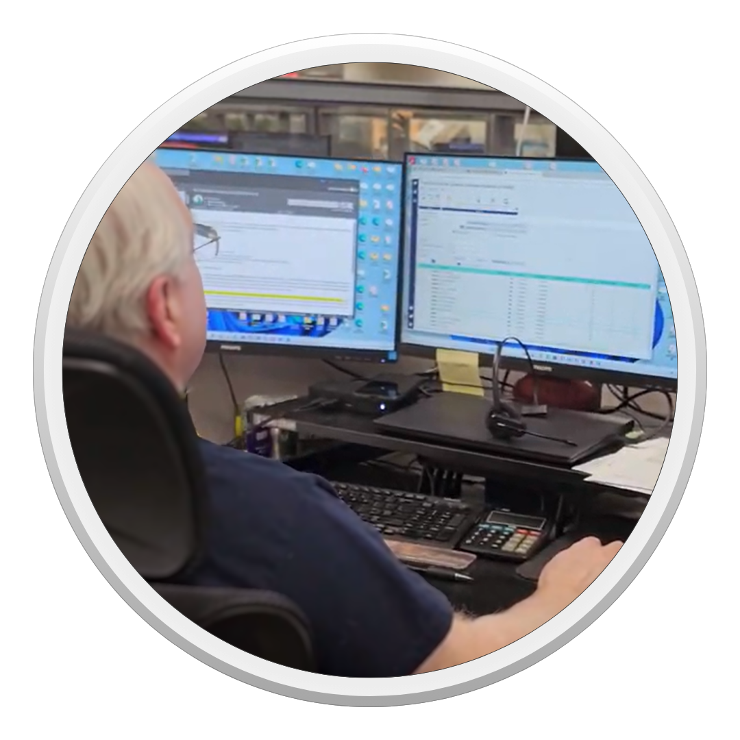 A man is sitting in front of two computer monitors.