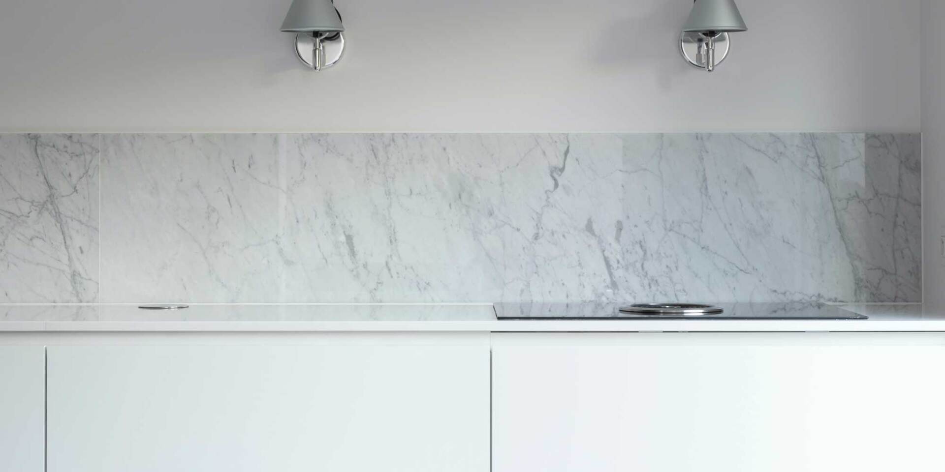 A gray marble backsplash gives texture to this sleek white kitchen.