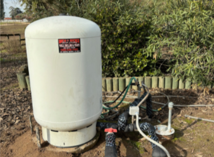 A well covered in snow with a wooden bench next to it.