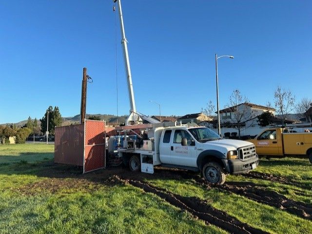 A white truck is parked in a grassy field next to a yellow truck.