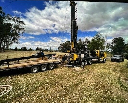 A truck with a trailer attached to it is parked in a field.