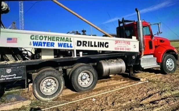 A man is lifting a bucket out of a hole in the ground.