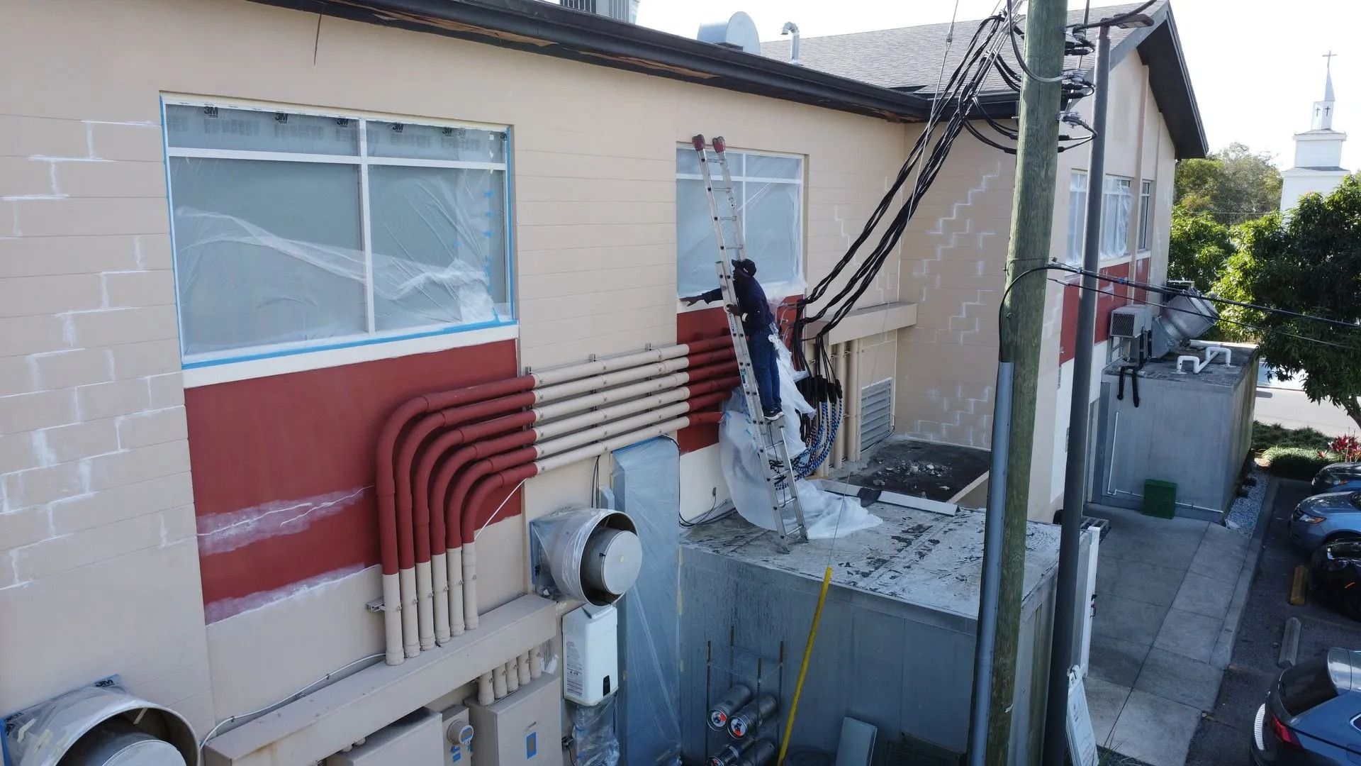 Exterior of a building with electrical equipment, utility pole, and parked cars.