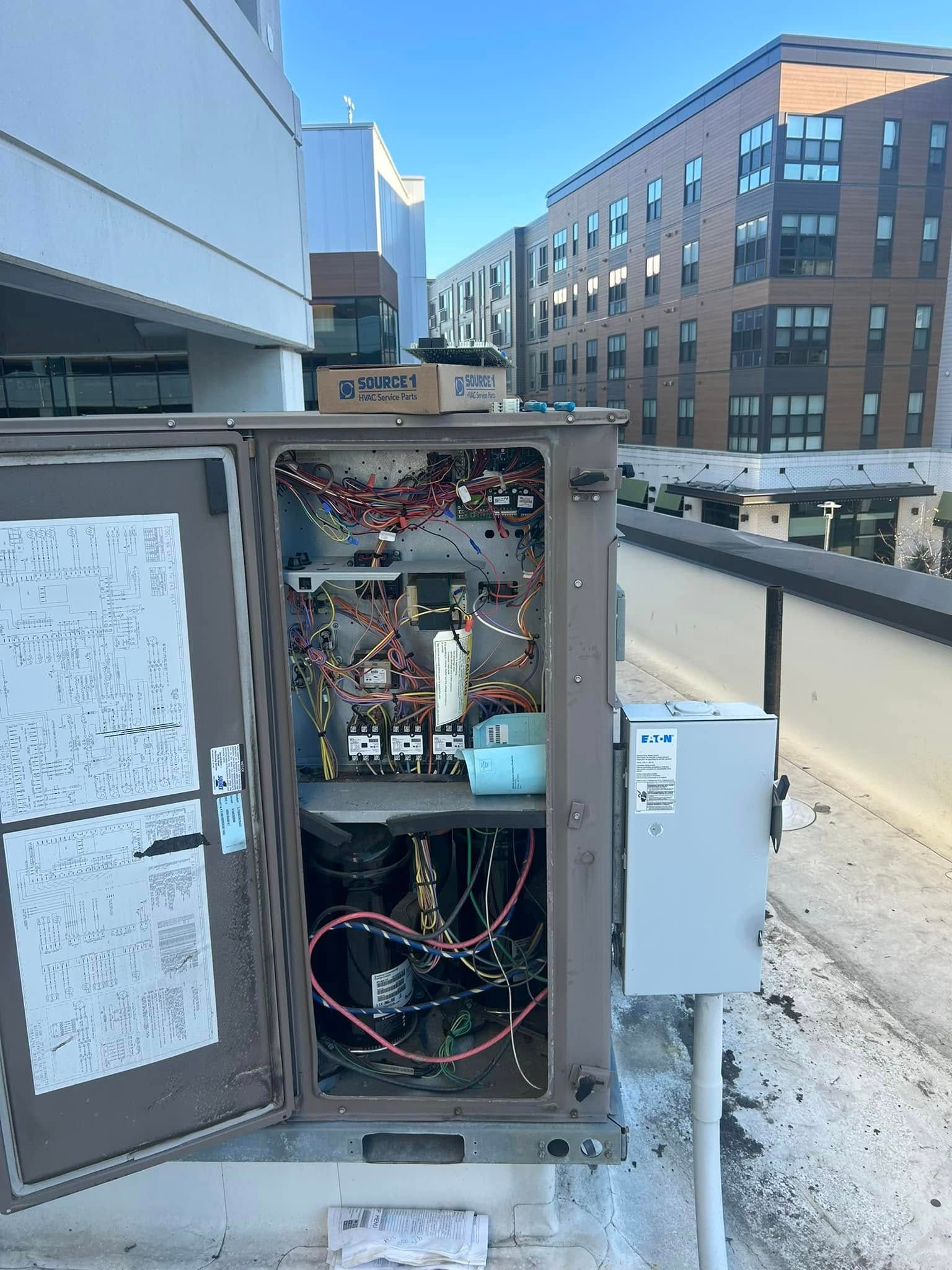A box with the door open and a lot of wires coming out of it.