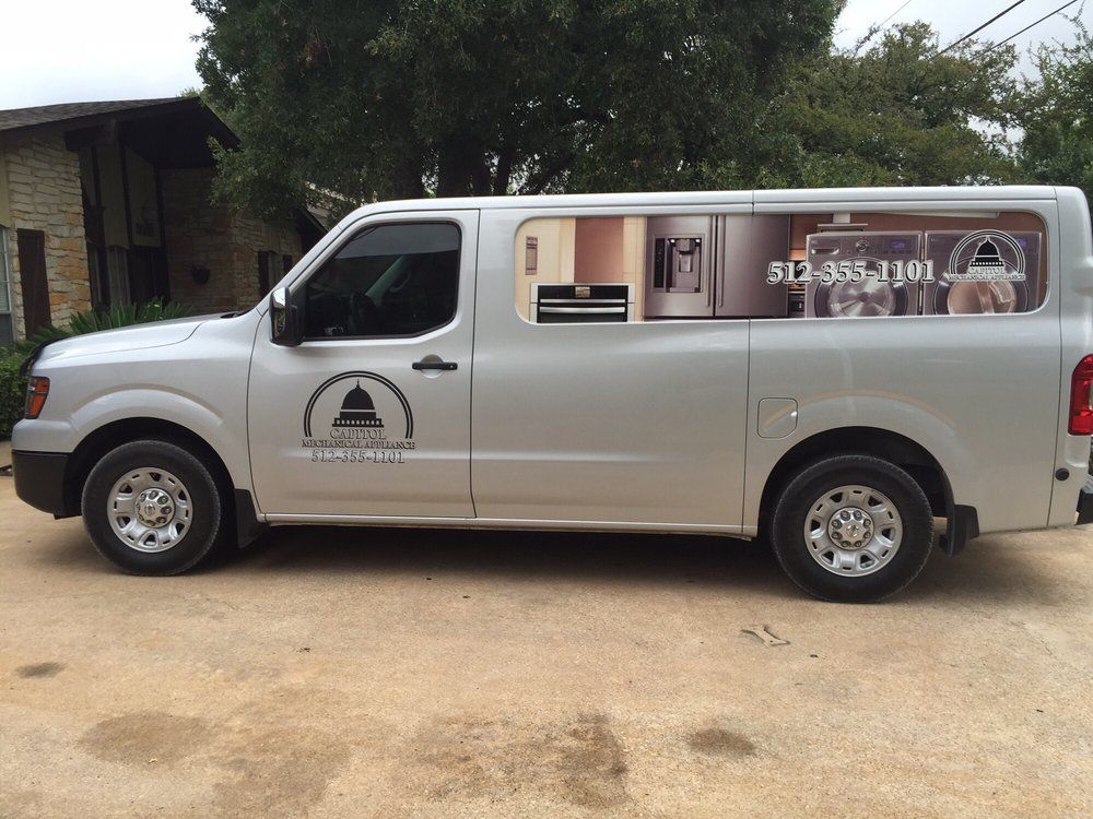 Silver van with company logo and kitchen advertisement on the side, parked outdoors.